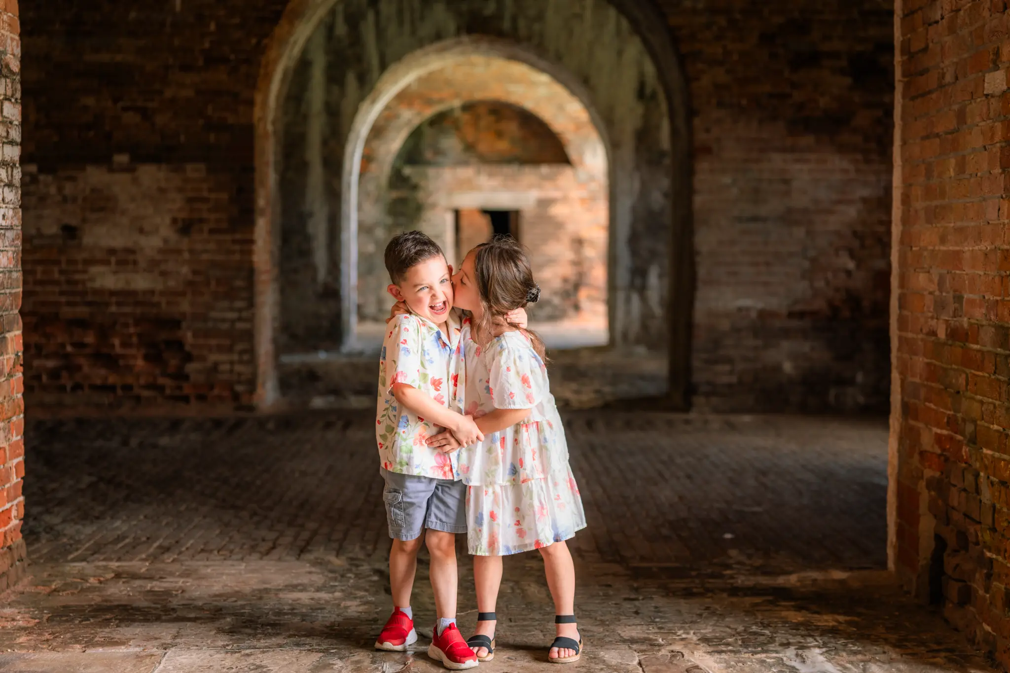 Two children sharing a hug inside a historic brick arch